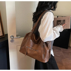 Detail of vintage brown large capacity PU leather tote bag with functional side zippers