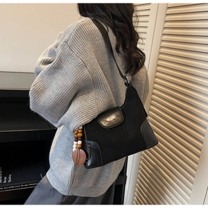 Close-up of black matte leather dumpling bag with silver buckle and beaded charm detail