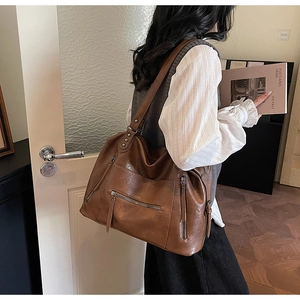 Detail of vintage brown tote bag showing multiple zipper pockets and rivet reinforcement