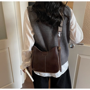 Detail of dark brown saddle bag with vintage geometric jacquard strap in bright interior