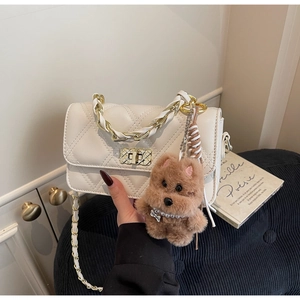 Close-up of white quilted chain bag with gold twist lock and a plush dog charm