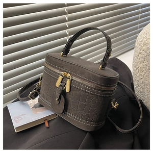 Detailed view of crocodile pattern leather bucket bag with gold zipper and strap