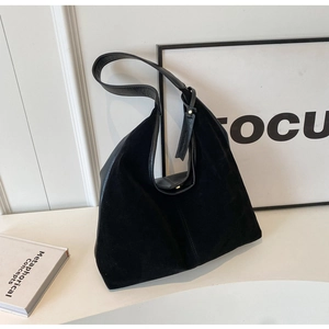 Close-up of black suede and leather tote bag featuring a magnetic metal buckle and tag