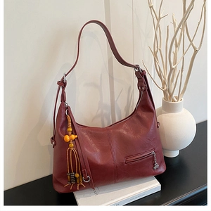 Détail du sac cabas bordeaux avec pompon en perles de bois et tirette trèfle en métal