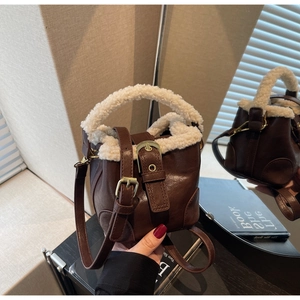 Détail d'un mini sac seau en cuir marron avec bordure en simili laine blanche et boucles