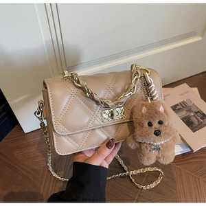 Close-up of beige quilted crossbody bag with gold twist lock and plush puppy charm