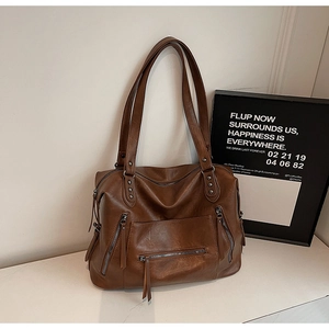 Close-up of brown vintage tote bag with multiple zipper pockets and leather tassels