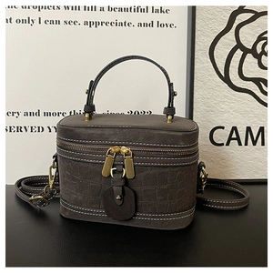 Detail of dark brown faux crocodile bucket bag with white stitching and gold hardware