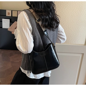 Detail of black hobo bag with vintage patterned wide strap on model in indoor setting