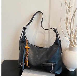 Détail du grand sac Hobo noir avec perles en bois orange et breloque trèfle en métal