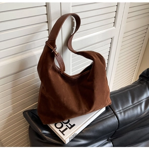 Detail of a large dark brown suede hobo shoulder bag with textured vertical stitching