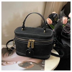 Detail of black bucket bag with crocodile leather trim and gold zipper accents