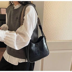 Retro black leather bucket bag with wide geometric strap styled on a model