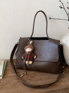 Borsa tote retrò marrone scuro con ciondolo a forma di orso su un tavolo vintage