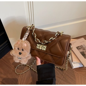 Top view of brown quilted crossbody bag with gold twist lock and plush bear charm