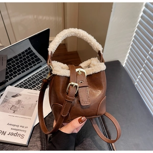 Détail du sac seau vintage en similicuir marron avec finitions en peau de mouton blanche