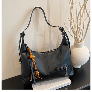 Détail du sac cabas en similicuir noir avec texture grainée et pendentif décoratif perlé