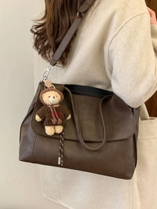 Borsa tote marrone in ecopelle con ciondolo a orsetto indossata con cappotto beige