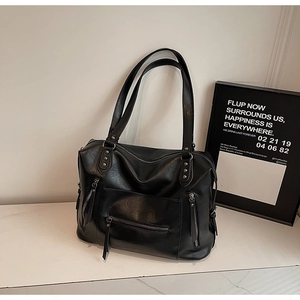 Close-up of black PU leather motorcycle bag with metal zippers and long leather pullers