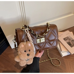 Detail of brown quilted shoulder bag with gold twist lock and a cute plush dog charm