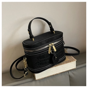 Detail of crocodile embossed leather vanity bag with white contrast stitching and gold zipper