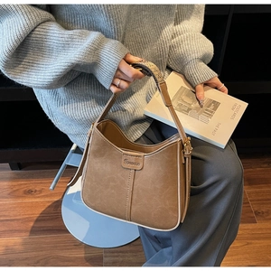 Detail of vintage brown leather hobo bag with woven strap and textured surface finish