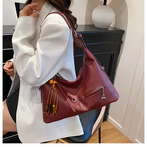 Détail du sac cabas en cuir bordeaux avec pompon en perles jaunes et poche zippée