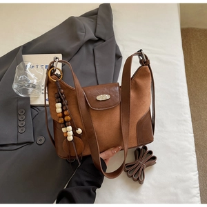Close-up of brown suede and leather dumpling bag with beaded tassel and metal hardware