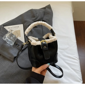 Détail du sac seau en cuir noir avec bordure en peluche blanche et boucle dorée