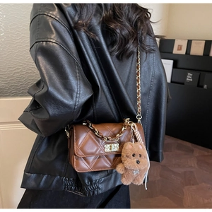 Brown quilted crossbody bag with a metal chain strap and a cute teddy bear charm