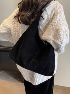 Minimalist black velvet hobo bag with large capacity, worn with white knit sweater