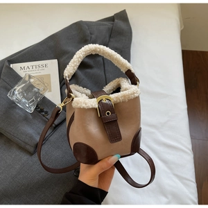 Détail d'un sac seau en similicuir marron avec garniture en fausse fourrure blanche et métal