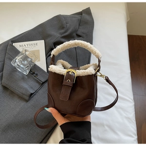 Détail du sac seau vintage marron avec bordure en laine blanche et boucles dorées