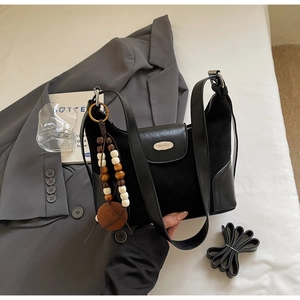 Detail of black patchwork dumpling bag featuring suede texture and metallic logo plaque