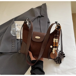 Close-up of brown suede hobo bag with gold fashion buckle and beaded tassel detail