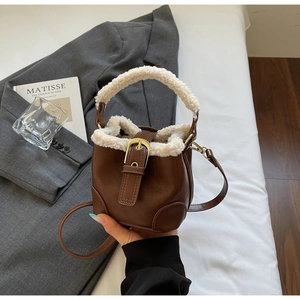 Détail d'un sac seau marron avec bordure en peluche et boucle dorée chic
