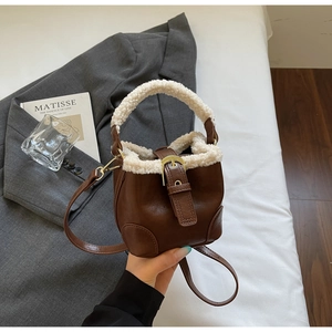 Détail du sac seau en cuir marron avec bordure en fausse fourrure blanche et boucle dorée