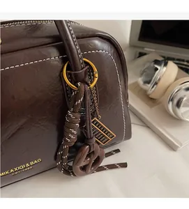 Gros plan du sac porté épaule rétro en cuir marron avec surpiqûres blanches et breloques