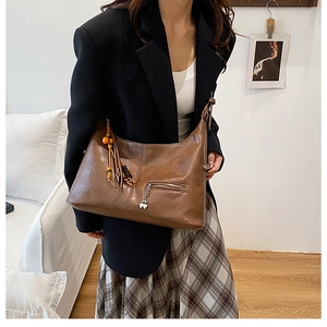 Détail du grand sac cabas marron foncé avec pompon en bois et pendentif trèfle