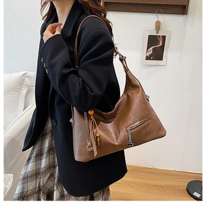 Détail du sac cabas marron avec chaîne trèfle et gland décoratif en perles orange de style chic