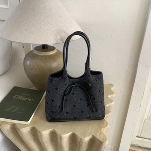 Close-up of textured polka dot tote bag with a sleek black leather bow detail