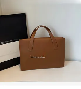 Dettaglio della borsa tote in pelle marrone con texture liscia e doppi manici robusti