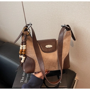 Detail of vintage patchwork shoulder bag featuring suede texture and wooden bead charm