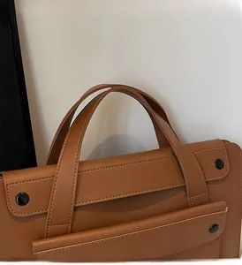 Vista macro di una borsa in pelle marrone con doppi manici resistenti e grana finissima
