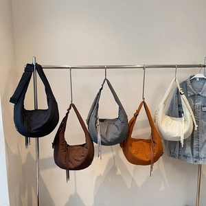 Detail of colorful nylon crescent crossbody bags hanging on a rack with zip tassels