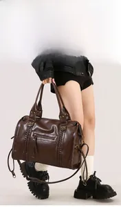 Dettaglio della borsa tote in pelle marrone scuro con trama intrecciata e borchie