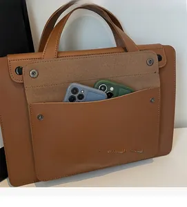 Dettaglio della tasca frontale di una borsa in pelle marrone con due cellulari