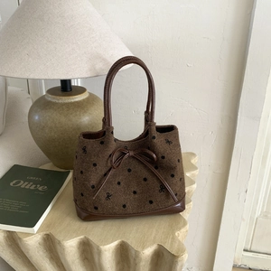Detailed texture of brown polka dot tweed tote bag with leather trim on a side table