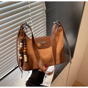Close-up of matte brown dumpling bag featuring wooden beads and FASHION metal plaque
