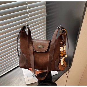 Detail of retro brown dumpling bag showing suede leather contrast and wood bead charm